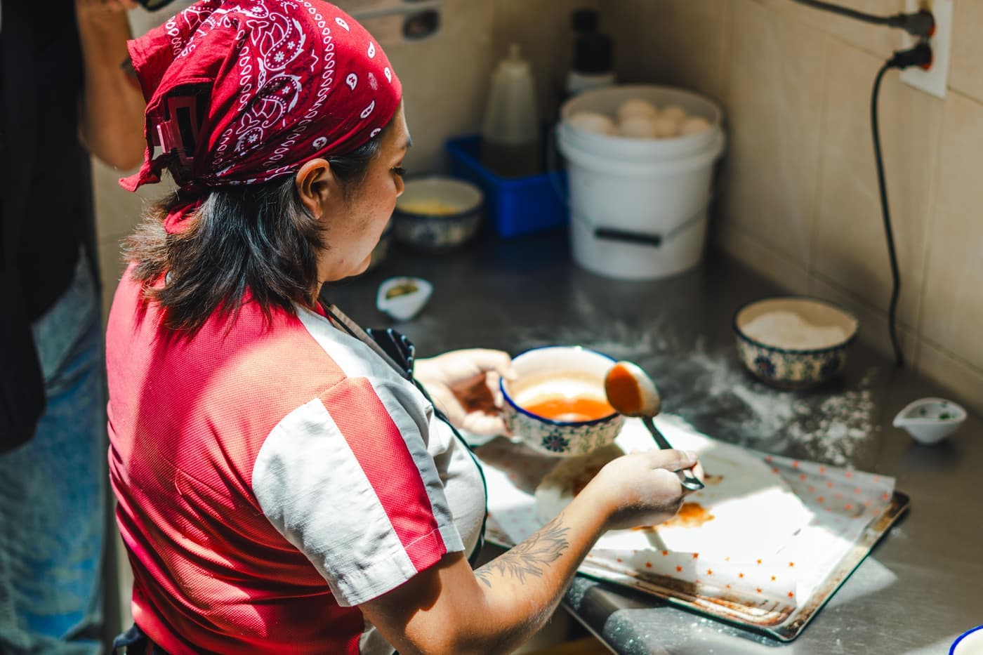 A home cook working on a pizza in a bright kitchen