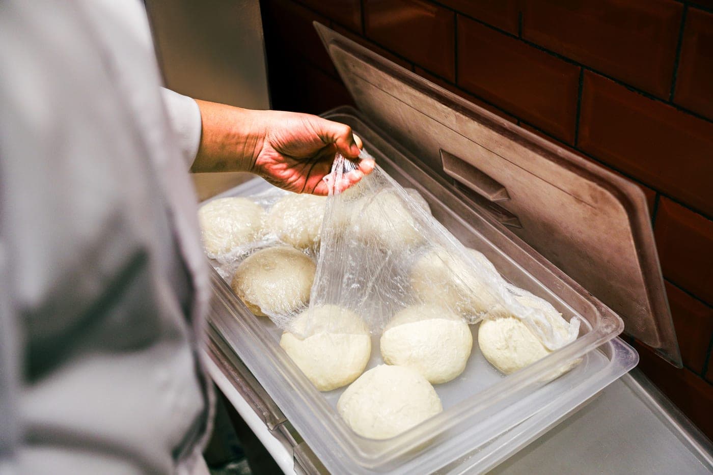 Balls of pizza dough resting in lidded containers