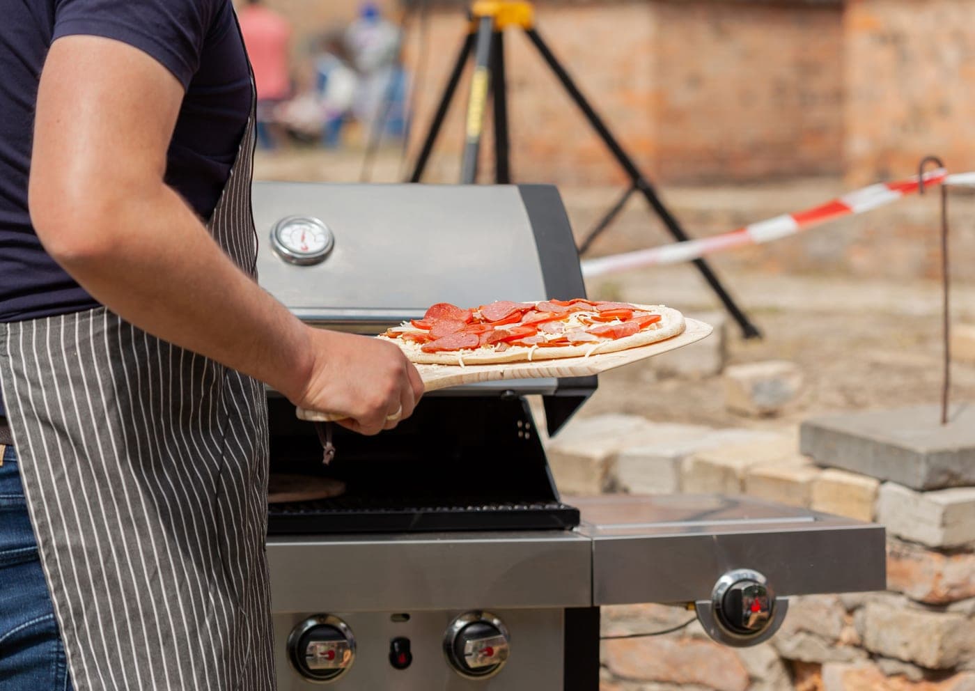 A pizza cooking over an outdoor grill