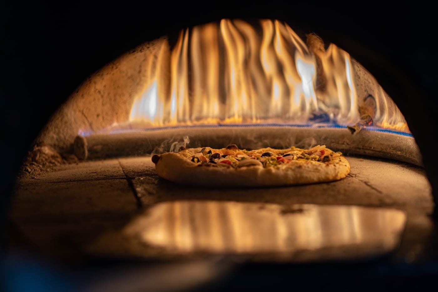 A pizza baking on a hot stone inside an oven